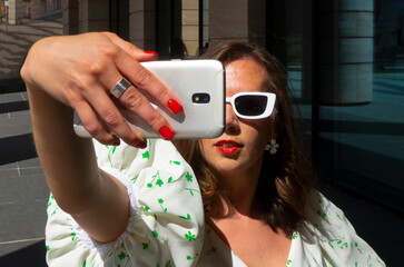Woman make selfie with smartphone in paris, france. Woman with mobile phone on colorful background. Girl in sunglasses with fashion look and sensual beauty. New technology and modern life. High