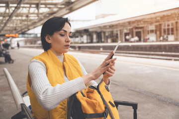 young woman holding passport and tickets, and waiting for train at railway station Enjoying travel concept