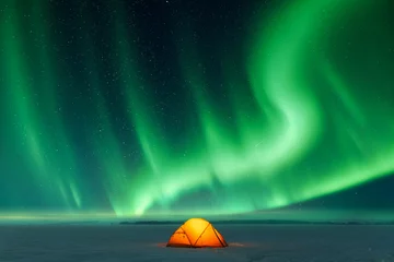 Poster Orange tent lighted from the inside against the backdrop of incredible sky with Northern lights. Aurora borealis in winter field © Ivan Kmit