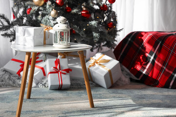 Glowing lantern with Christmas gift boxes on table in festive bedroom