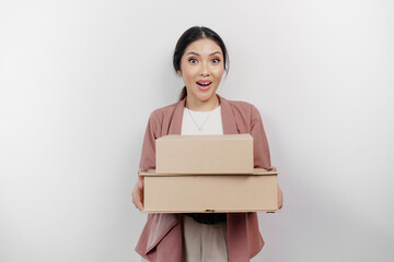 Obraz premium Surprised young Asian woman employee wearing cardigan while holding stack of cardboard boxes, isolated by white background