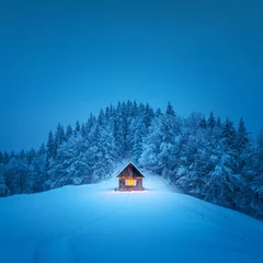 Foto op Canvas A winter scene with a solitary wooden cabin and snow-covered fir trees in the midst of a forested mountain meadow. Christmas postcard. Snowy mountains forest © Ivan Kmit