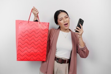 An excited beautiful young Asian woman employee wearing cardigan is carrying shopping bag and her...