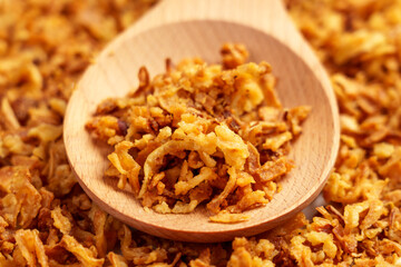 Crispy fried onions in wooden spoon. Roasted shallot flakes