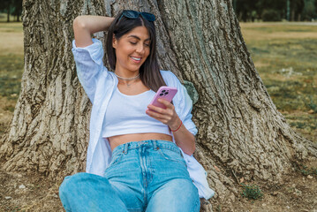 Beautiful Brunette Woman using her phone in the summer park