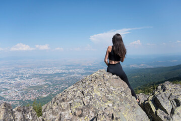 Woman sitting on a rocks in the summer mountain above the city of Sofia	
