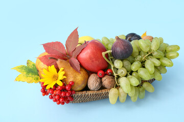 Wicker basket with different fresh fruits on blue background