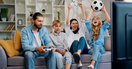 Happy family playing video game at home sitting on the couch. Entertainment and modern lifestyle...