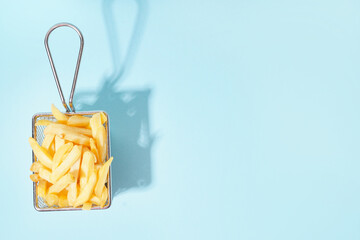 French fries in metal basket on blue background