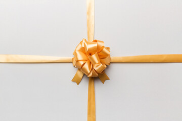Top view of gold ribbon rolled and yellow bow isolated on colored background. Flat lay with copy space