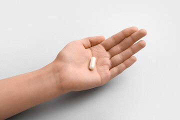 Female hand with capsule on white background