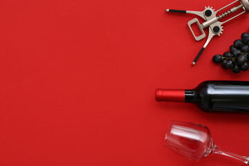 Glass and bottle of exquisite wine with corkscrew on red background - obrazy, fototapety, plakaty