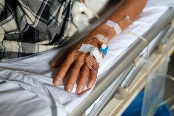 Close up photo of Elderly man's hand with IV drip infusion in treatment session on the bed in...