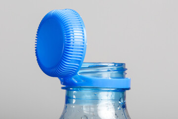 Close up of new cap attached to plastic bottle, connected to the neck of the bottle by solid tab attached to safety ring. They are intended to encourage recycling, as part of the fight against litter. - obrazy, fototapety, plakaty