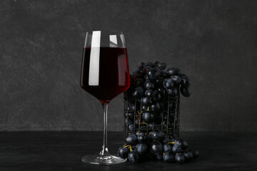 Glass of exquisite wine with grapes on black background