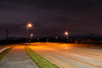 Fototapeta na wymiar Airplane Light Trails in Cloudy Night Sky over Road