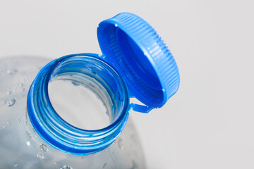 Close up of new cap attached to plastic bottle, connected to the neck of the bottle by solid tab...