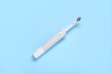 Electric toothbrush on blue background.