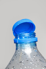 Close up of new cap attached to plastic bottle, connected to the neck of the bottle by solid tab...