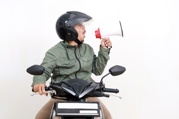 Happy asian man announcing something using megaphone while driving a motorcycle. Isolated on white background