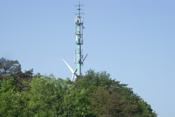 Mobilfunkmast in einem Waldstück vor einer Windkraftanlage