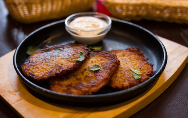 Fried grated potato pancakes with sour cream on frying pan
