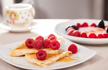 Breakfast of pancakes with fresh raspberries on table