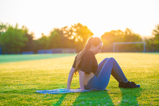 young woman doing yoga on green grass during sunrise early summer morning