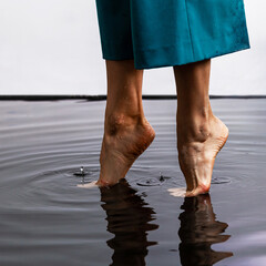 Amazing walking on water. Woman barefoot walking on the surface of the water floor. Close up legs...