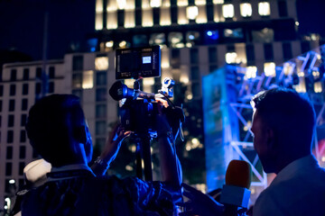 Camera man recording while organizing scene with interviewer at night event