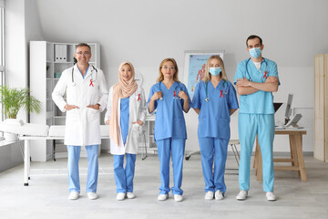 Professional team of doctors with red ribbons in clinic. World AIDS Day concept