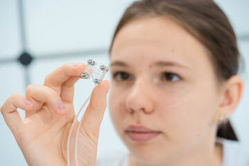 young woman holding lab on chip microfluidics in her hands