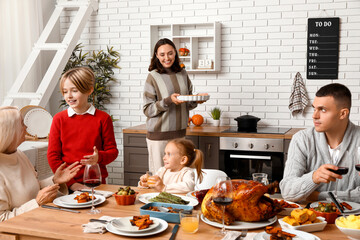 Happy family having dinner at festive table on Thanksgiving Day