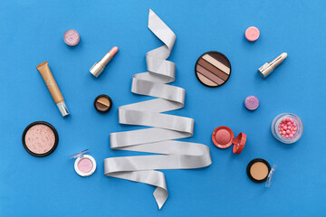 Different decorative cosmetics and Christmas decor on blue background