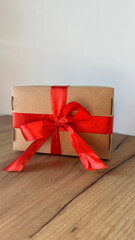 Brown gift box and red ribbon on wooden background with space