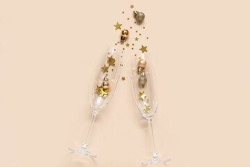 Beautiful composition with champagne glasses and decorations for New Year party on beige background