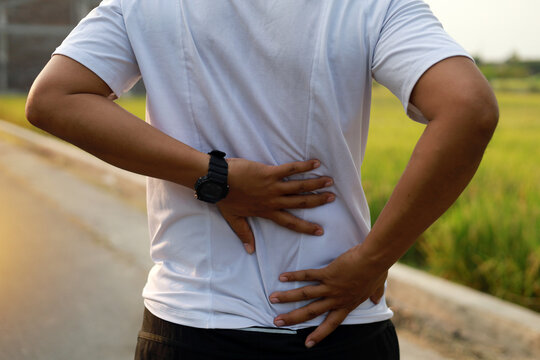 Close up photo of Asian Man with back pain during doing outdoor exercise.