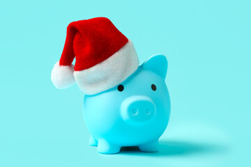 Piggy bank with Santa hat on blue background