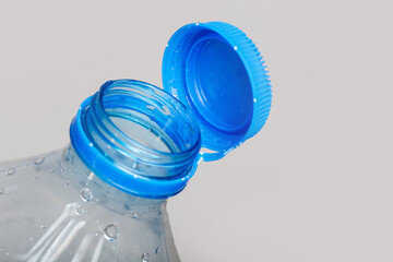 Close up of new cap attached to plastic bottle, connected to the neck of the bottle by solid tab...