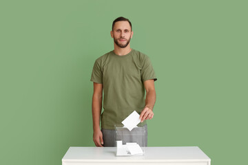 Voting man near ballot box on green background