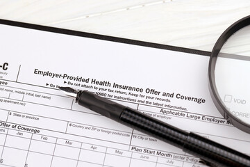 IRS Form 1095-C Employer-Provided Health Insurance Offer, and Coverage tax blank on A4 tablet lies...