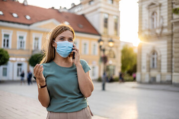 Fototapeta premium Business woman with protective mask talking on phone outdoor.