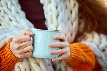 Cropped portrait of young girl covered blanket holding warming hot cup of coffee, tea or hot...