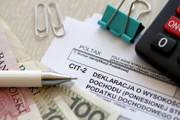 Declaration of the amount of earned income or incurred loss by corporate income tax payer, CIT-2 tax forms on accountant table with pen and polish zloty money bills close up