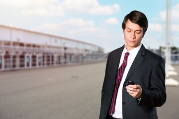 Successful young man walking on street, hold phone