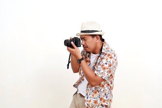 Asian adult man tourist standing while photographing sideways. Concept of travel. Isolated on white background