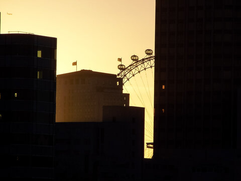 The London Eye is captured between office blocks during sunrise.