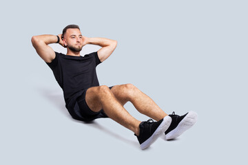 Obraz premium Focused handsome strong young caucasian man with beard in sportswear make exercises for abs