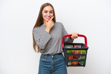 Young Rumanian woman holding a shopping basket full of food isolated on white background happy and smiling