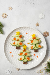 Christmas tree sandwiches with cream cheese and cucumber on a light background, top view